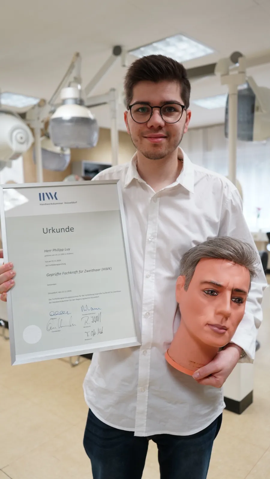 Philipp Luy mit seiner Urkunde der Handwerkskammer: geprüfte Fachkraft für Zweithaar